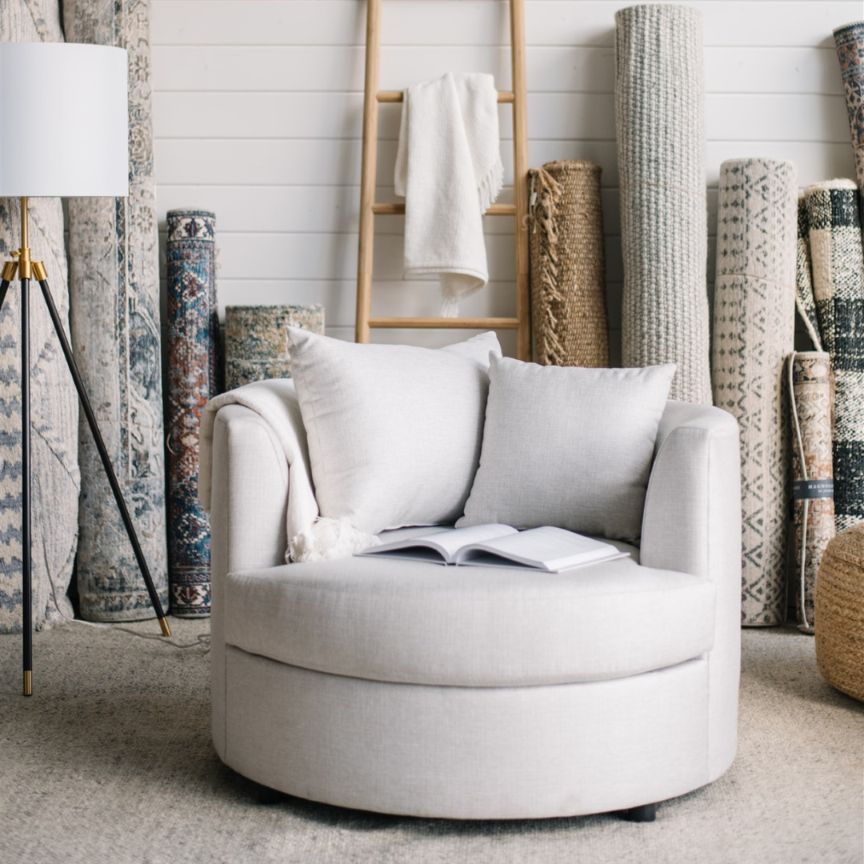 Gray cuddle chair with a book in a room with decorative rugs and a lamp in St. Albert, Alberta